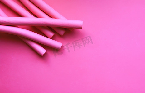 柔和的粉彩背景上的粉红色泡沫卷发器。