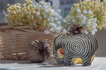 综艺奇葩说摄影照片_一套大象形状的陶瓷杯，里面有干的西伯利亚奇葩种子和编织篮子里的一束鲜花，用来装饰房子很漂亮。