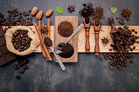 烤咖啡豆与咖啡粉和美味的配料，在深色石头背景下制作美味的咖啡。