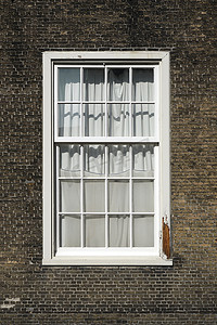 带窗户的砖墙摄影照片_“棕色砖墙背景上的旧木窗，带小窗的石墙”