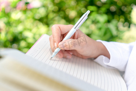 女人手写在白色的小笔记本上，记下不要忘记或做清单计划。