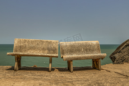 海边两把抛光的旧石椅靠在一起。