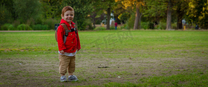 阳光明媚的夜晚，可爱的小男孩站在公园里