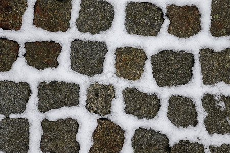 冬天，一条古老的鹅卵石路上的白雪表面。