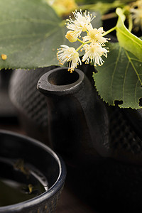 木制茶壶摄影照片_茶壶和杯子用菩提树茶和花