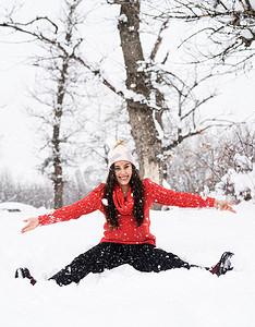 玩雪摄影照片_穿着红色毛衣的黑发年轻女子在公园里玩雪