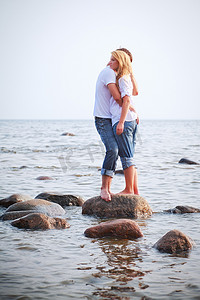 情侣拥抱在海中的一块石头上