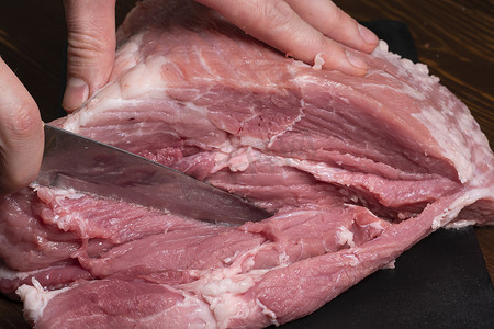 在特写镜头中用刀将猪肉或牛肉切成薄片。肉类菜肴和食品的准备。烤羊肉串、烧烤或烤肉串用的红肉片。用刀切生鲜肉。食谱