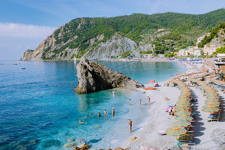 椅子和遮阳伞填满了 spiaggia di fegina 海滩，这是意大利 Monterosso 宽阔的沙滩村，是意大利五渔村的一部分