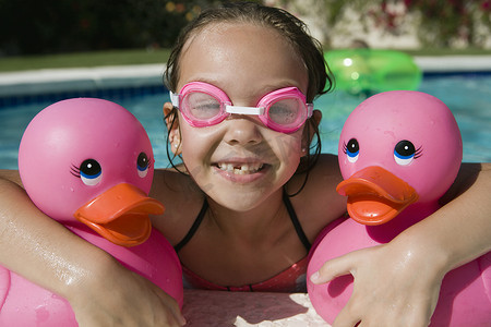 儿童泳摄影照片_泳池边拿着粉红色橡皮鸭的女孩