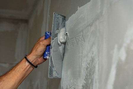 老体力工人用抹墙工具装修房子