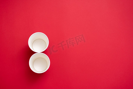 两个数字 8 形状的空纸杯。在红色背景上。