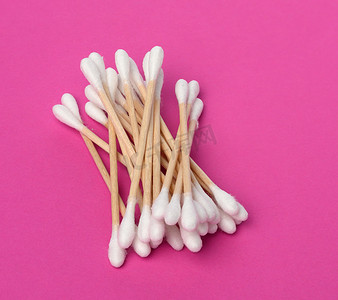 粉红色背景中带白色棉毛的木棍，卫生用品