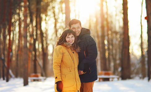 在森林里散步的年轻跨种族微笑夫妇的温暖冬日肖像