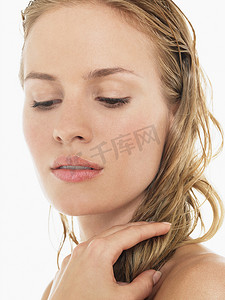 年轻的金发女人低头看着，拿着湿头发特写