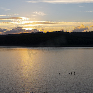 三人在埃菲尔国家公园日落时在平静的 Rursee 湖游泳