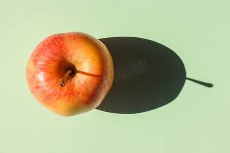 一个在纯色背景上有硬阴影的苹果。