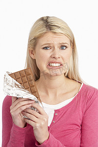 看起来有罪的年轻女人在工作室里吃大块巧克力