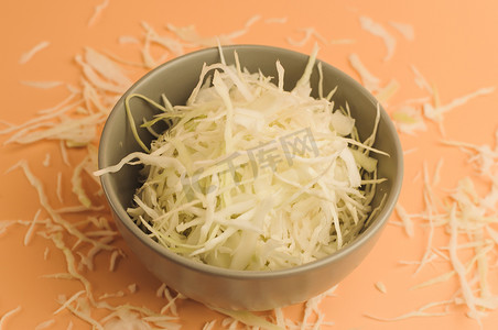 米色背景上切碎的白菜、碗里和表面周围的白菜、极简风格的切碎白菜、乡村蔬菜、素食产品、维生素、健康饮食理念。