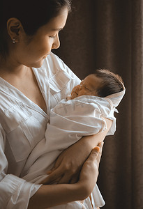 特写年轻女子在她的怀里抱着一个刚出生的婴儿。