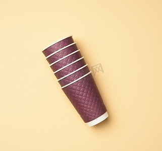 餐具包装摄影照片_米色背景中的一堆紫色一次性纸杯