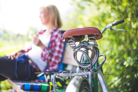 复古自行车之旅：户外自行车座椅、乡村场景、坐在模糊背景中的金发女孩