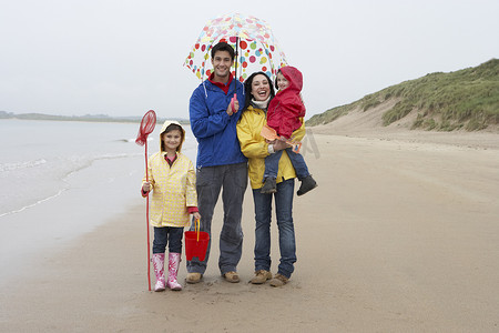 带伞的女孩摄影照片_沙滩上带伞的幸福家庭