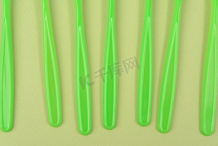绿色背景中的一堆绿色塑料叉子