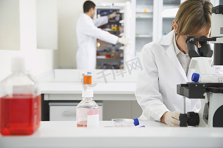 科学家使用显微镜，第二位科学家在实验室里看冰箱