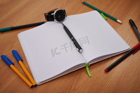 各种各样的书摄影照片_空白的笔记本手表周围散落着各种各样的文具用品。