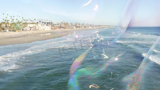 在加利福尼亚州的海洋码头上吹肥皂泡，夏季背景模糊。