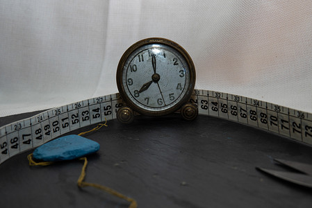 时钟被针、线和缝纫卷尺等缝纫用具包围。