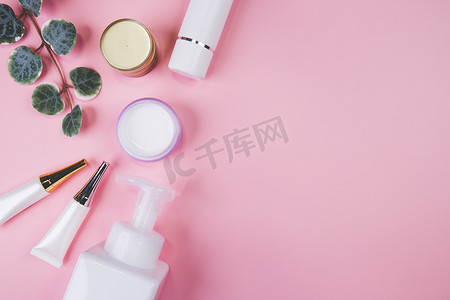 带奶油或乳液和叶子的化妆品瓶模型隔离在粉红色背景中，用于广告、护肤或美容的模型包装、顶视图、平躺、皮肤护理和产品治疗。