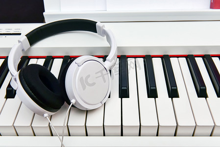 白色耳机躺在电子钢琴的键盘上