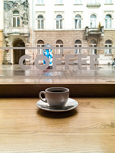 茶字摄影照片_窗前咖啡馆里的小白咖啡杯，上面贴着咖啡字贴