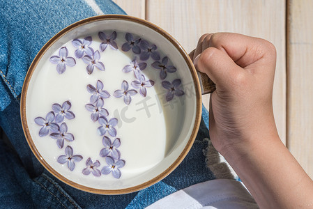 杯子用牛奶和小紫色丁香花用手