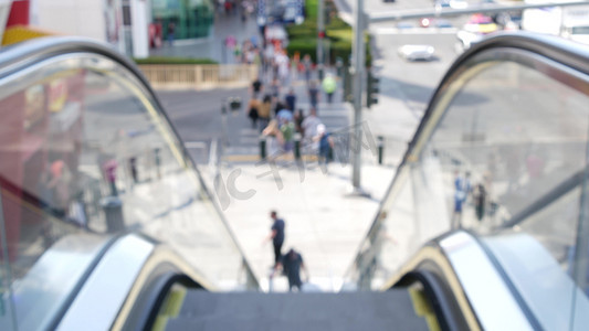 道路人群摄影照片_通过自动扶梯的透视图，在美国拉斯维加斯大道的道路交叉口人行横道上散焦的无法辨认的人群。