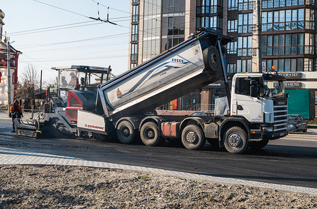 KYIV, UKRAINE - September 10, 2020：工业沥青摊铺机在街上的道路施工现场铺设新鲜沥青。