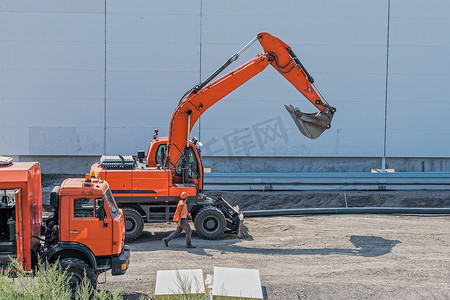 大型工程摄影照片_施工期间现场的工头和大型设备、挖掘机和卡车