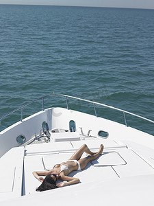 在豪华游艇上享受日光浴的比基尼年轻女性的高视角
