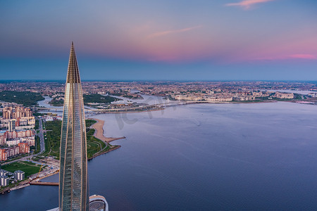 俄罗斯，圣彼得堡，2021 年 5 月 16 日：粉红色夕阳下欧洲最高摩天大楼拉赫塔中心的无人机视角，俄罗斯天然气工业股份公司总部，背景为俄罗斯天然气工业股份公司竞技场