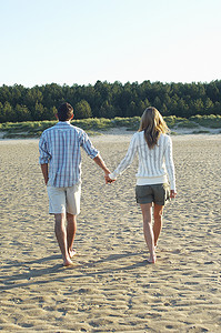 情侣手牵手背影走在沙滩上