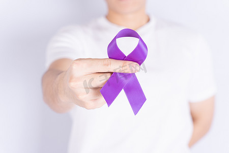 世界癌症日，双手握着灰色背景的紫色丝带。