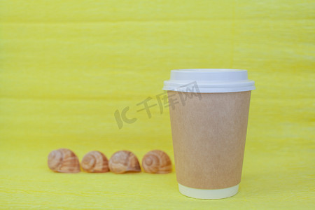 白色咖啡杯盖摄影照片_盖着白色盖子的纸杯咖啡，旁边是海壳