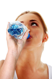 蓝色的矿泉水瓶子摄影照片_从瓶子里喝矿泉水的少女特写镜头。