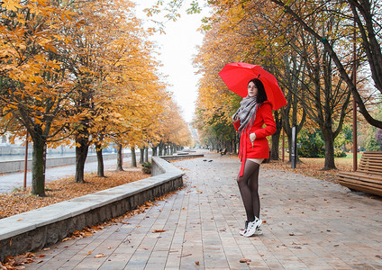 撑着雨伞摄影照片_穿着红色外套、撑着雨伞站在巷子里的小女孩