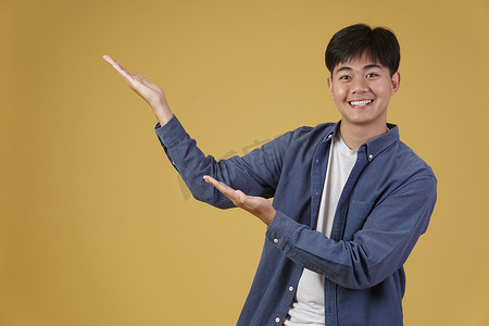 快乐英俊的亚洲年轻男子穿着随意，在 copyspace 摆出张开手掌的姿势。
