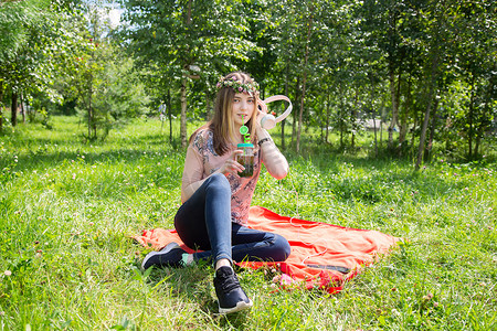 一个小女孩在夏天坐在公园的草坪上听音乐