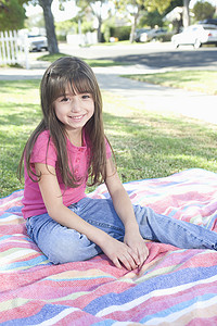 野餐毯摄影照片_坐在野餐毯上的年轻女孩