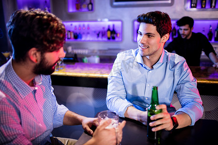 朋友们在酒吧柜台互相交流并喝啤酒